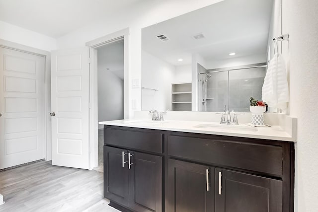 bathroom with wood-type flooring, vanity, and a shower with shower door