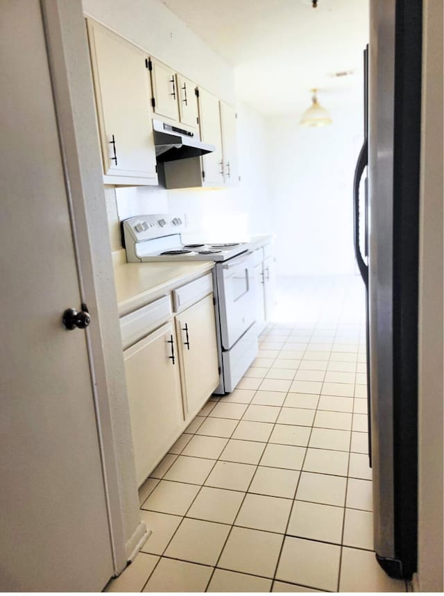 kitchen with stainless steel fridge, stove, white cabinets, and light tile patterned floors