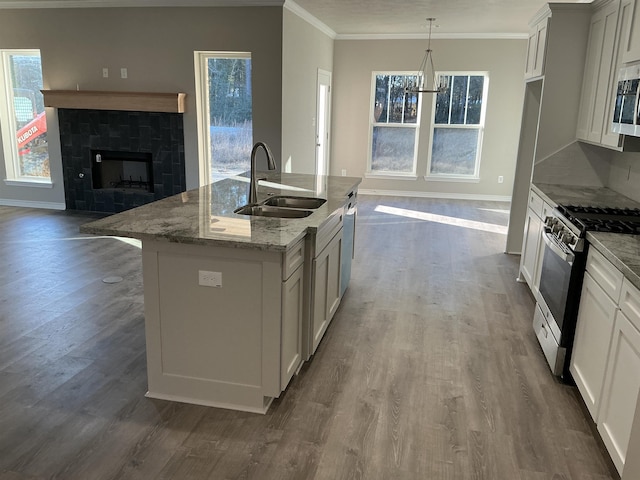 kitchen with sink, light stone counters, hanging light fixtures, a center island with sink, and stainless steel appliances