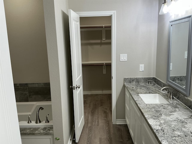 bathroom with wood-type flooring, a washtub, and vanity