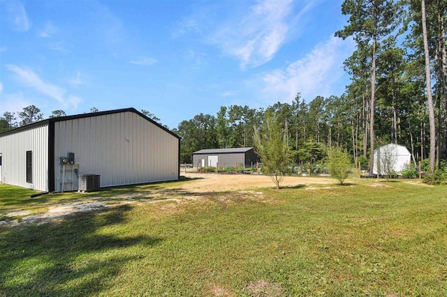 view of yard featuring an outbuilding, central AC unit, and a pole building