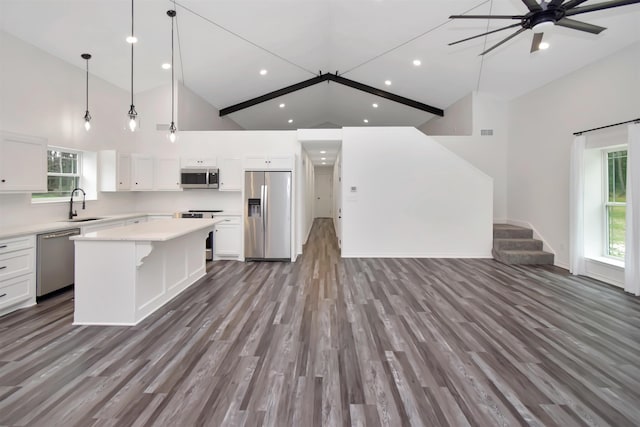 kitchen with open floor plan, a center island, appliances with stainless steel finishes, white cabinets, and light countertops