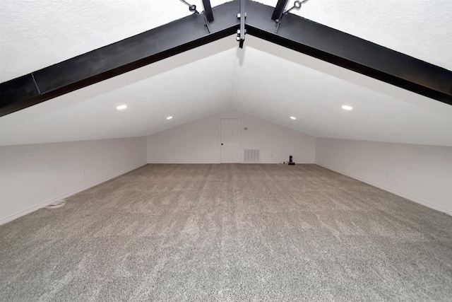 additional living space featuring visible vents, light colored carpet, baseboards, and vaulted ceiling