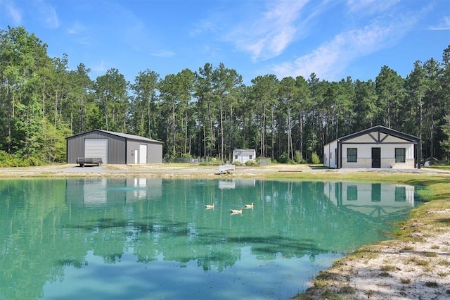 view of swimming pool with an outbuilding, a view of trees, and a water view