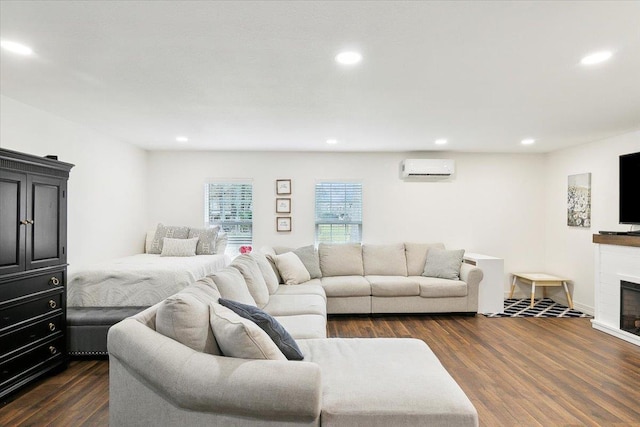 living room featuring a tiled fireplace, an AC wall unit, and dark hardwood / wood-style floors