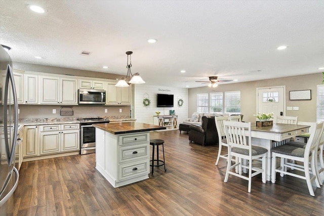 kitchen with wooden counters, a textured ceiling, a kitchen island, pendant lighting, and stainless steel appliances