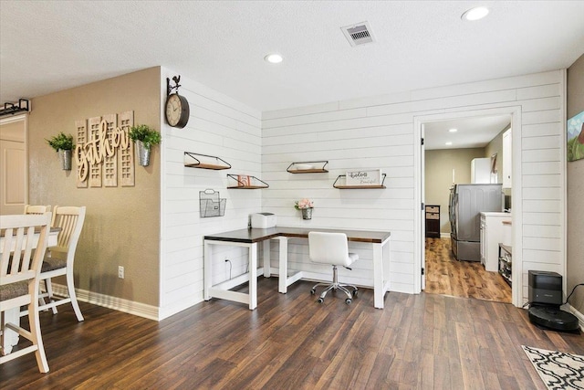 office area featuring dark hardwood / wood-style flooring, a textured ceiling, and wood walls