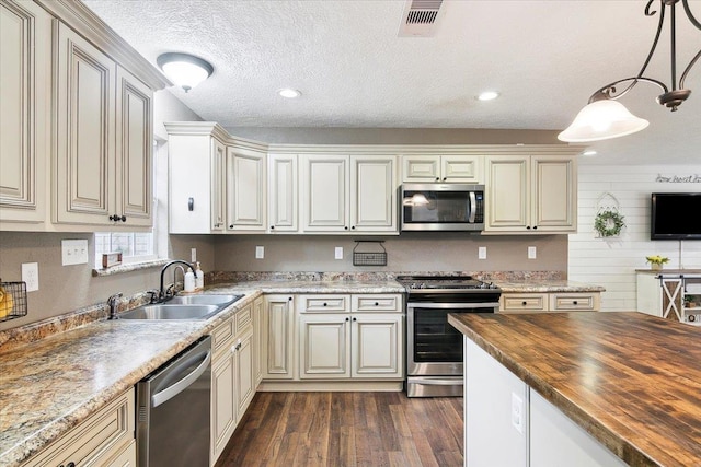 kitchen featuring butcher block countertops, decorative light fixtures, sink, stainless steel appliances, and a textured ceiling