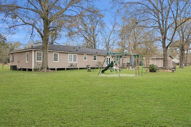 back of property with cooling unit, a yard, and a playground