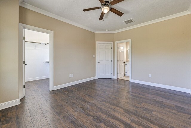 450 Jackson St, Beaumont, TX 77701 - unfurnished bedroom featuring dark wood-style floors, ornamental molding, baseboards, a walk in closet, and a textured ceiling