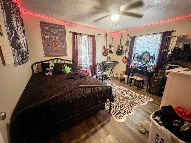 bedroom featuring multiple windows, ceiling fan, a textured ceiling, and hardwood / wood-style flooring