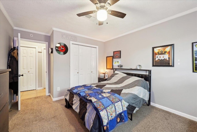 carpeted bedroom with baseboards, ornamental molding, ceiling fan, and a closet