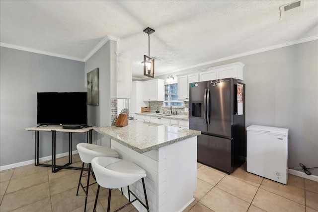 kitchen with fridge, stainless steel fridge, ornamental molding, and white cabinetry