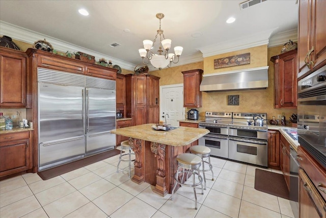 7510 Shadow Creek Dr, Beaumont, TX 77707 - kitchen featuring appliances with stainless steel finishes, wall chimney range hood, a breakfast bar, a chandelier, and light tile patterned floors