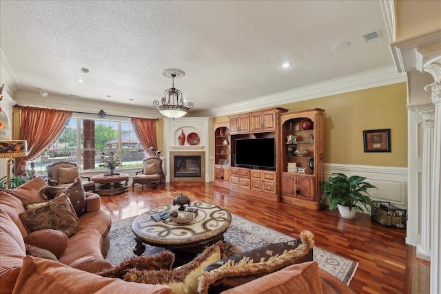 7510 Shadow Creek Dr, Beaumont, TX 77707 - living room featuring crown molding, a textured ceiling, wood finished floors, a fireplace, and ornate columns