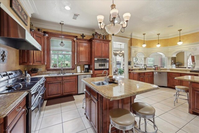 7510 Shadow Creek Dr, Beaumont, TX 77707 - kitchen with stainless steel appliances, a chandelier, wall chimney range hood, a breakfast bar area, and decorative light fixtures