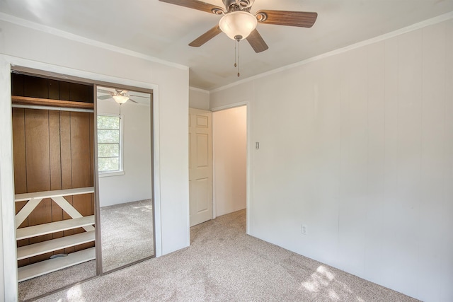 unfurnished bedroom featuring carpet flooring, ceiling fan, a closet, and crown molding