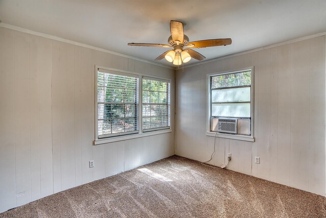 carpeted spare room featuring wood walls, ceiling fan, cooling unit, and ornamental molding