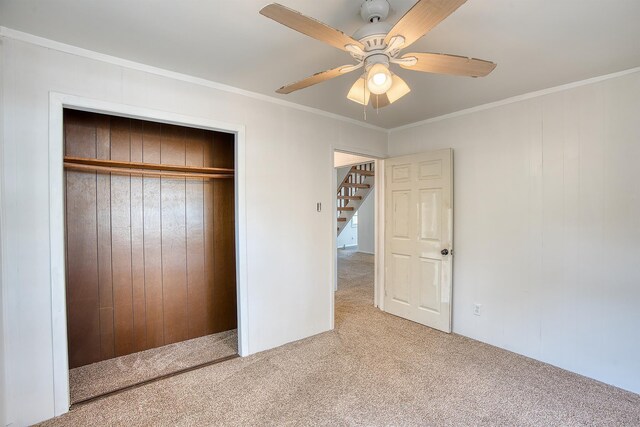 unfurnished bedroom with ceiling fan, carpet floors, ornamental molding, and a closet