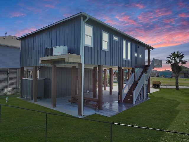 back house at dusk with a lawn and a patio