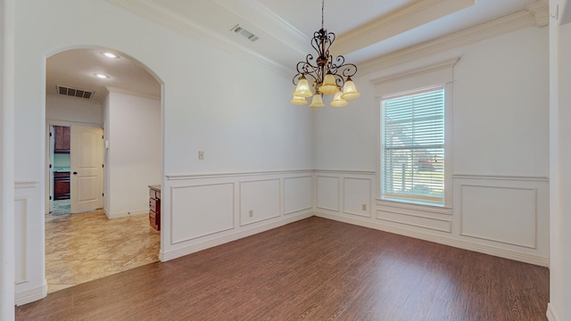 unfurnished room with arched walkways, visible vents, a tray ceiling, and wood finished floors