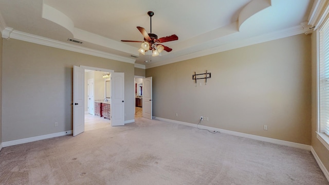 unfurnished bedroom featuring baseboards, visible vents, a raised ceiling, light colored carpet, and crown molding