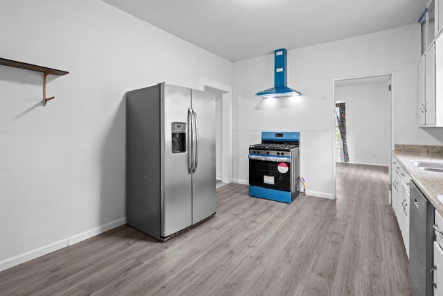 kitchen featuring appliances with stainless steel finishes, light stone counters, white cabinets, light wood finished floors, and extractor fan