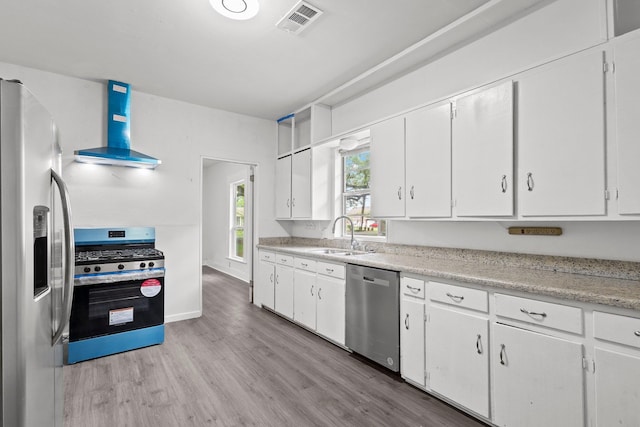 kitchen featuring visible vents, extractor fan, light wood-type flooring, a sink, and appliances with stainless steel finishes