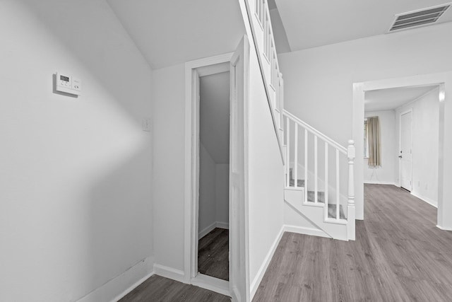 stairway featuring baseboards, wood finished floors, and visible vents