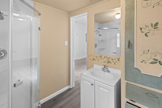 bathroom with vanity, ornamental molding, wood finished floors, baseboards, and a shower stall