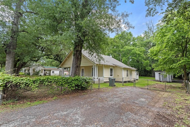 view of front facade with an outdoor structure, a gate, fence, and a shed