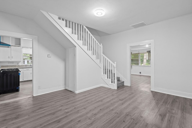 unfurnished living room with visible vents, baseboards, stairs, and wood finished floors