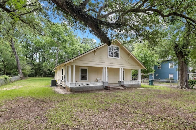 bungalow-style home featuring fence, a front lawn, a porch, and central AC