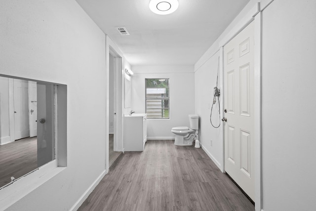 interior space featuring visible vents, a sink, baseboards, and wood finished floors