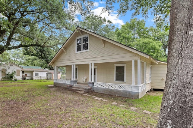 view of front of property featuring a front lawn, fence, and covered porch