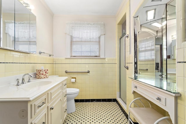 bathroom featuring vanity, crown molding, tile walls, toilet, and a shower with shower door