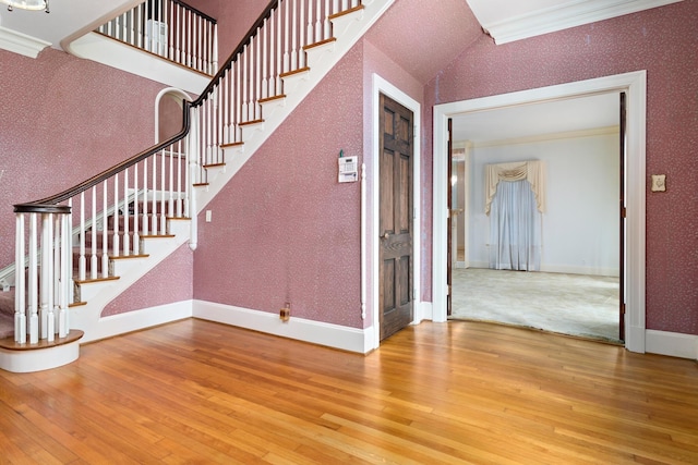 staircase with hardwood / wood-style floors, lofted ceiling, and crown molding