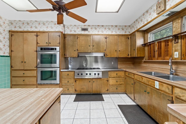 kitchen with backsplash, sink, ceiling fan, light tile patterned floors, and stainless steel appliances