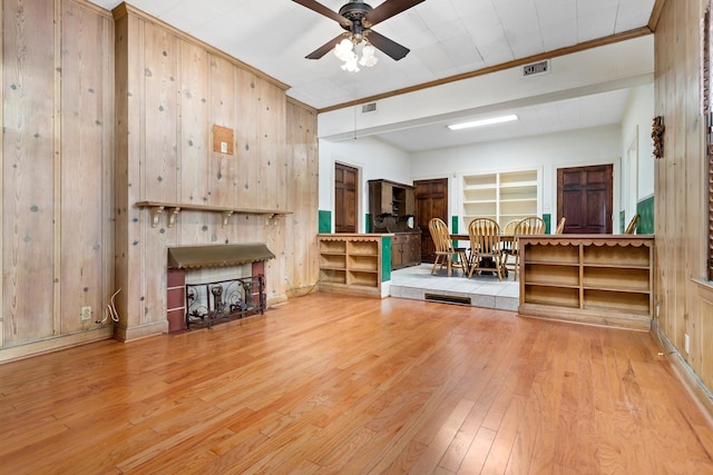 living room with wood walls, ceiling fan, light hardwood / wood-style floors, and ornamental molding