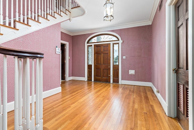 entryway featuring hardwood / wood-style floors, crown molding, and an inviting chandelier