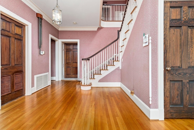 foyer featuring a notable chandelier, light hardwood / wood-style floors, and crown molding