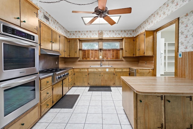 kitchen with ceiling fan, light tile patterned flooring, sink, and stainless steel appliances