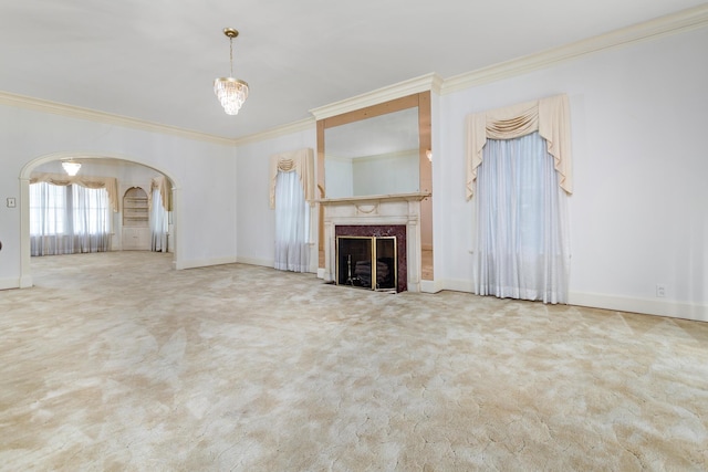 unfurnished living room with a high end fireplace, carpet floors, ornamental molding, and a notable chandelier