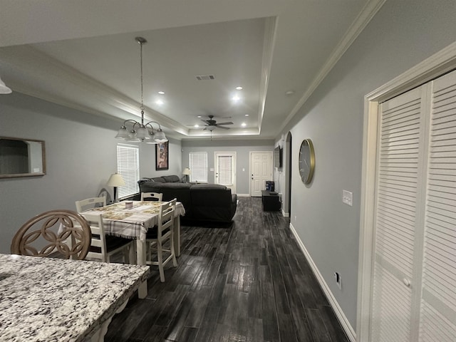 dining room with a tray ceiling, ceiling fan, crown molding, and dark wood-type flooring