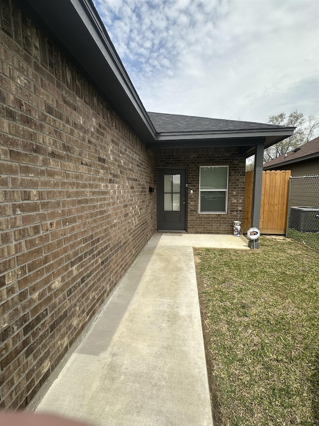 property entrance with a lawn and a patio area