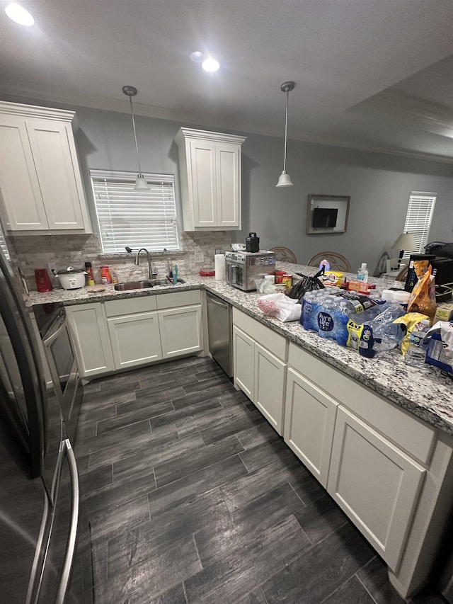 kitchen featuring white cabinetry, sink, hanging light fixtures, backsplash, and appliances with stainless steel finishes