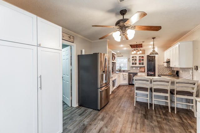 kitchen featuring appliances with stainless steel finishes, tasteful backsplash, a breakfast bar, white cabinetry, and hanging light fixtures