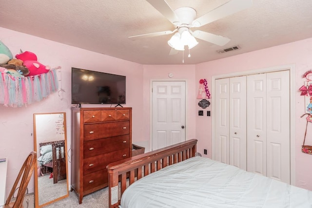 carpeted bedroom featuring a textured ceiling, a closet, and ceiling fan