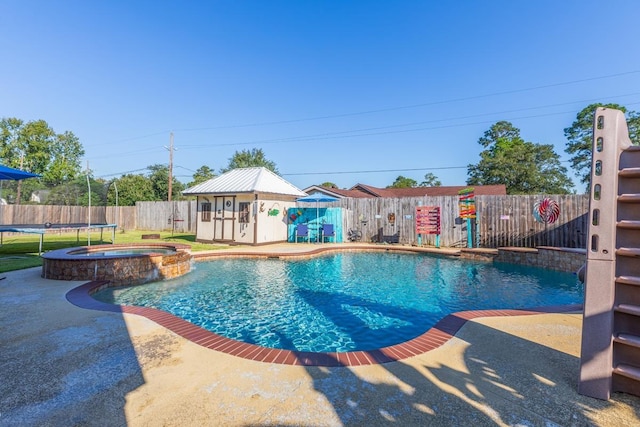 view of pool with a patio area, an in ground hot tub, an outdoor structure, and a trampoline