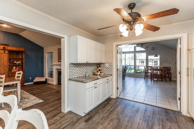 kitchen featuring lofted ceiling, dark stone counters, ceiling fan, dark hardwood / wood-style flooring, and white cabinetry